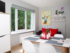 a dining room with a white table and red pillows at Phoenix apartment in Jūrmala