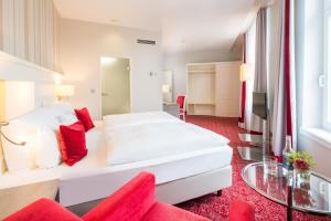 a bedroom with a large white bed and a red carpet at Steigenberger Hotel Bielefelder Hof in Bielefeld