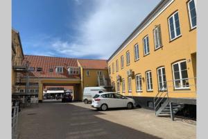 a white car parked in a parking lot next to buildings at Lejlighed på Torvet i Stege in Stege