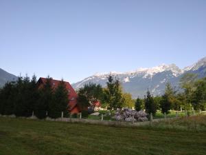 un granero rojo en un campo con montañas al fondo en Počitniška hiša Nad Sočo, en Bovec