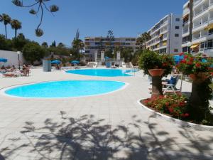 a swimming pool in a resort with flowers and buildings at Aloe Friendly Holiday Home in Playa del Ingles
