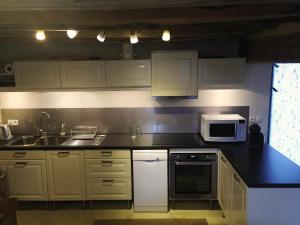 eine Küche mit weißen Schränken, einer Spüle und einer Mikrowelle in der Unterkunft Un Figuier dans notre Jardin in Beaune-la-Rolande
