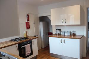 a kitchen with white cabinets and a black stove at Deal Cottage 5 minutes walk to the beach & Town centre in Deal