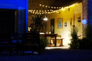 un patio iluminado con una mesa y luces en Les Sauges en Isigny-sur-Mer