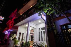 Ein weißes Gebäude mit einem Schild in der Nacht. in der Unterkunft 5.T Hostel in Hue