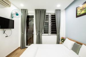 ein Schlafzimmer mit einem weißen Bett und einem Fenster in der Unterkunft 5.T Hostel in Hue