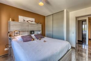 um quarto com uma grande cama branca com almofadas roxas em le panorama du lac em Annecy