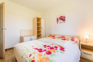 1 dormitorio con 1 cama con colcha de flores en Apartmaji BANONIA, en Veržej