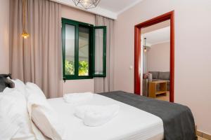 a bedroom with a white bed and a window at Arion Apartments in Skala Potamias