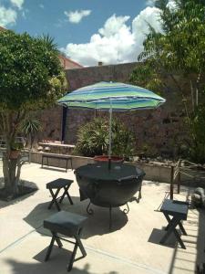 a large grill with an umbrella and two chairs at Hotel Mirador Real in Bernal