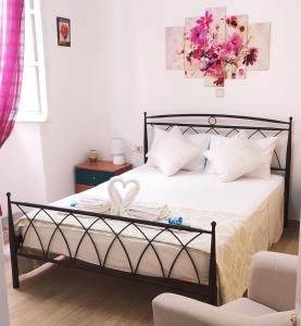 sypialnia z łóżkiem z białą pościelą i różowymi kwiatami w obiekcie Cofineta Apartment w Korfu