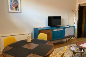een woonkamer met een tafel en een televisie bij Vichy Cocoon Appartements in Vichy