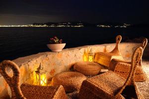 a table with wicker chairs and lights and the water at Kekrifalia Hotel in Skala