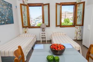 a room with two beds and a table with a bowl of tomatoes at Stefanos Studios in Skala