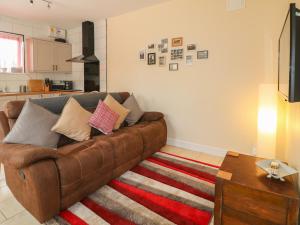 a living room with a brown couch and a rug at Church View Cottage in Rugeley