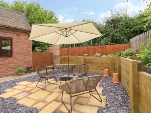 a patio with a table and chairs and an umbrella at Church View Cottage in Rugeley