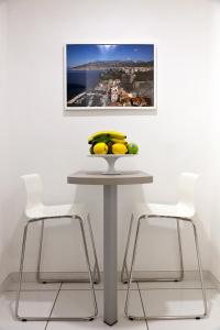 een tafel met twee stoelen en een fruitschaal erop bij YourHome - Maison Nonna Anna in Sorrento