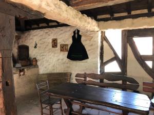 a dining room with a wooden table and a black dress hanging on the wall at Etnographic Houses in Dŭlbok Dol