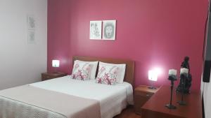 ノルデスチにあるLar de Santanaのピンクの壁のベッド1台、ランプ2つが備わるベッドルーム1室が備わります。