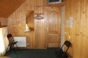 a room with wooden walls with two chairs and a door at Guest House Kalbakas in Smiltene