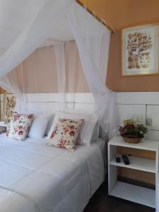 a bedroom with a white bed with a canopy at Magias de Paraty Ecopousada in Paraty