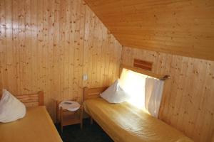 a bedroom with two beds in a wooden wall at Guest House Kalbakas in Smiltene