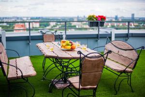 a table and chairs with a bowl of fruit on a balcony at Skyhouse Riga Amazing Penthouse and SPA in Rīga