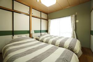 two beds in a room with a window at Mark's HOME in Maebashi