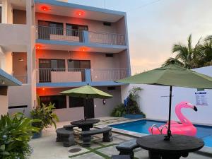 バラ・デ・ナビダードにあるHotel Del Marのプールとピンクのフラミンゴの傘が備わるリゾート