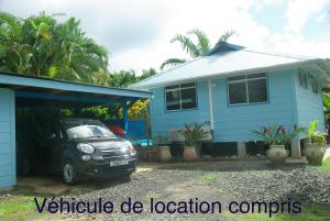 a car parked in front of a blue house at bungalow chez sofpat in Uturoa