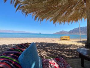a beach with a straw umbrella and the ocean at Sayadeen Village - Red Sea Riviera in Nuweiba