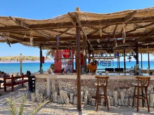 a bar on the beach with chairs and umbrellas at Sayadeen Village - Red Sea Riviera in Nuweiba