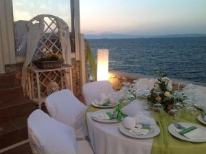 a table with white chairs and a table with the ocean at Kekrifalia Hotel in Skala