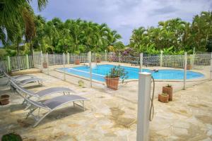 a swimming pool with two chairs next to a fence at Le Domaine de Boisvin in Sainte-Anne