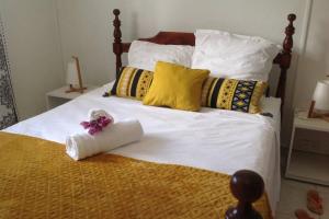 a bed with white sheets and yellow pillows at Le Domaine de Boisvin in Sainte-Anne +25 photos