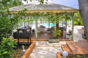 a gazebo with a table and a pool at Le Domaine de Boisvin in Sainte-Anne