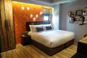 a bedroom with a large bed with an orange wall at Aspira D'Andora Sukhumvit 16 - Asoke in Bangkok