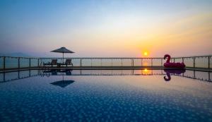 einen Pool mit Sonnenuntergang im Hintergrund in der Unterkunft Serene Beach Danang Hotel in Đà Nẵng