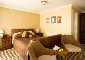 a hotel room with a bed and a chair at Raven Hotel by Greene King Inns in Hook