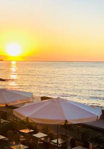 - un coucher de soleil sur l'océan avec des parasols sur une plage dans l'établissement VacanzeNaxos - Casa Frontemare, à Giardini Naxos