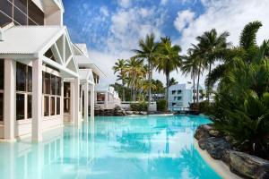 a swimming pool in front of a house with palm trees at Sheraton Grand Mirage Resort, Port Douglas in Port Douglas