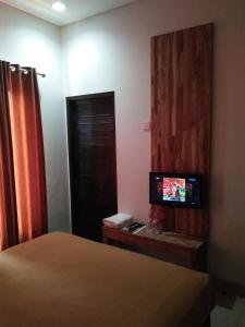 Antika Hotel في Rembang: غرفه فندقيه سرير وتلفزيون