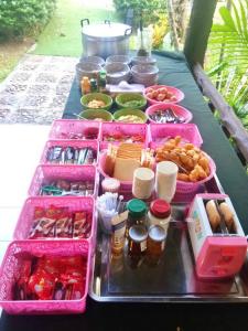 Baan Pak Rim Kuaen Resort في Ban Chieo Ko: طاولة مع صواني الطعام وردية اللون وغيرها من الأطعمة