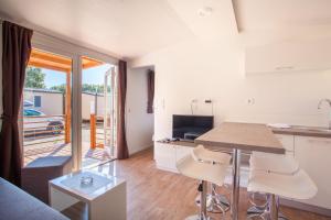 eine Küche und ein Wohnzimmer mit einem Tisch und Stühlen in der Unterkunft Mobile Homes Delta Marine at Campsite Rapoća in Nerezine