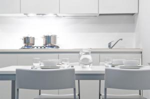 uma cozinha com mesas brancas e cadeiras brancas em Mecki Apartments em Nago-Torbole