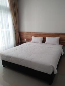 una camera da letto con un grande letto con lenzuola bianche di Antika Hotel a Rembang