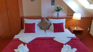 a bedroom with a large white bed with red pillows at Hotel Isabell Győr in Győr