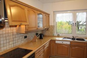 eine Küche mit Holzschränken und Spüle und einem Fenster in der Unterkunft Bike and Hike Ferienhaus Kolverath in Kolverath