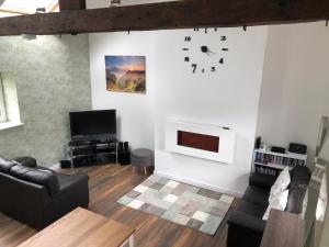 a living room with a couch and a clock on the wall at Plough Cottage in Bradfield