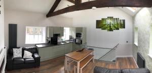 a living room with a table and a kitchen at Plough Cottage in Bradfield